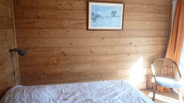 A wooden cabin room with a bed, a chair, and a framed picture on the wall. - Appartement Plain-pied Dans Chalet, Calme, Environnement Exceptionnel (Briançon)