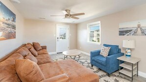 A living room with a brown sofa, a blue armchair, a small round table, and a lamp on a side table.