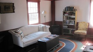 Un salon avec un canapé, une bibliothèque, une lampe et un fauteuil.