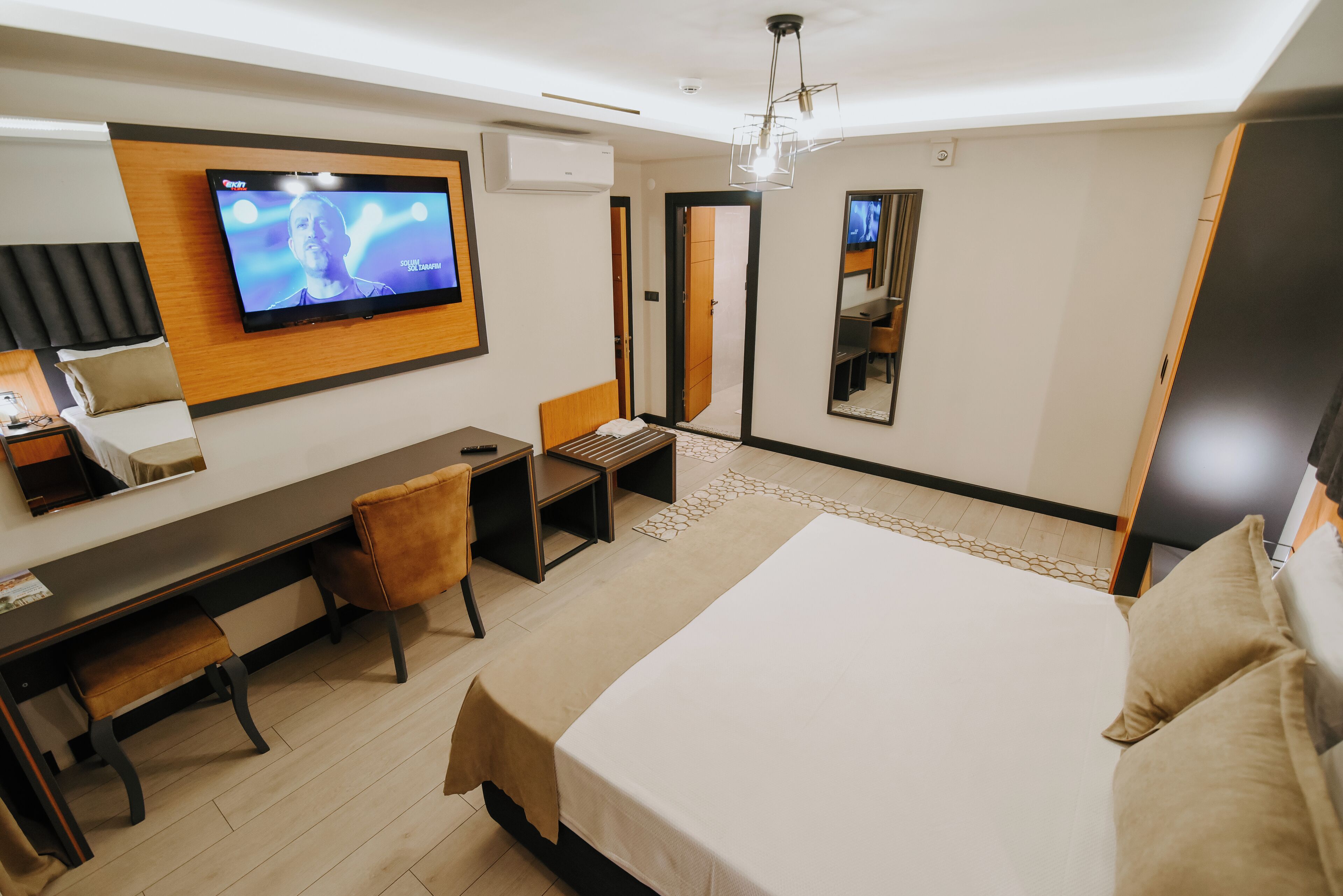Une chambre d’hôtel moderne équipée d’un grand lit, d’un bureau avec une chaise, d’une télévision et d’un miroir.
