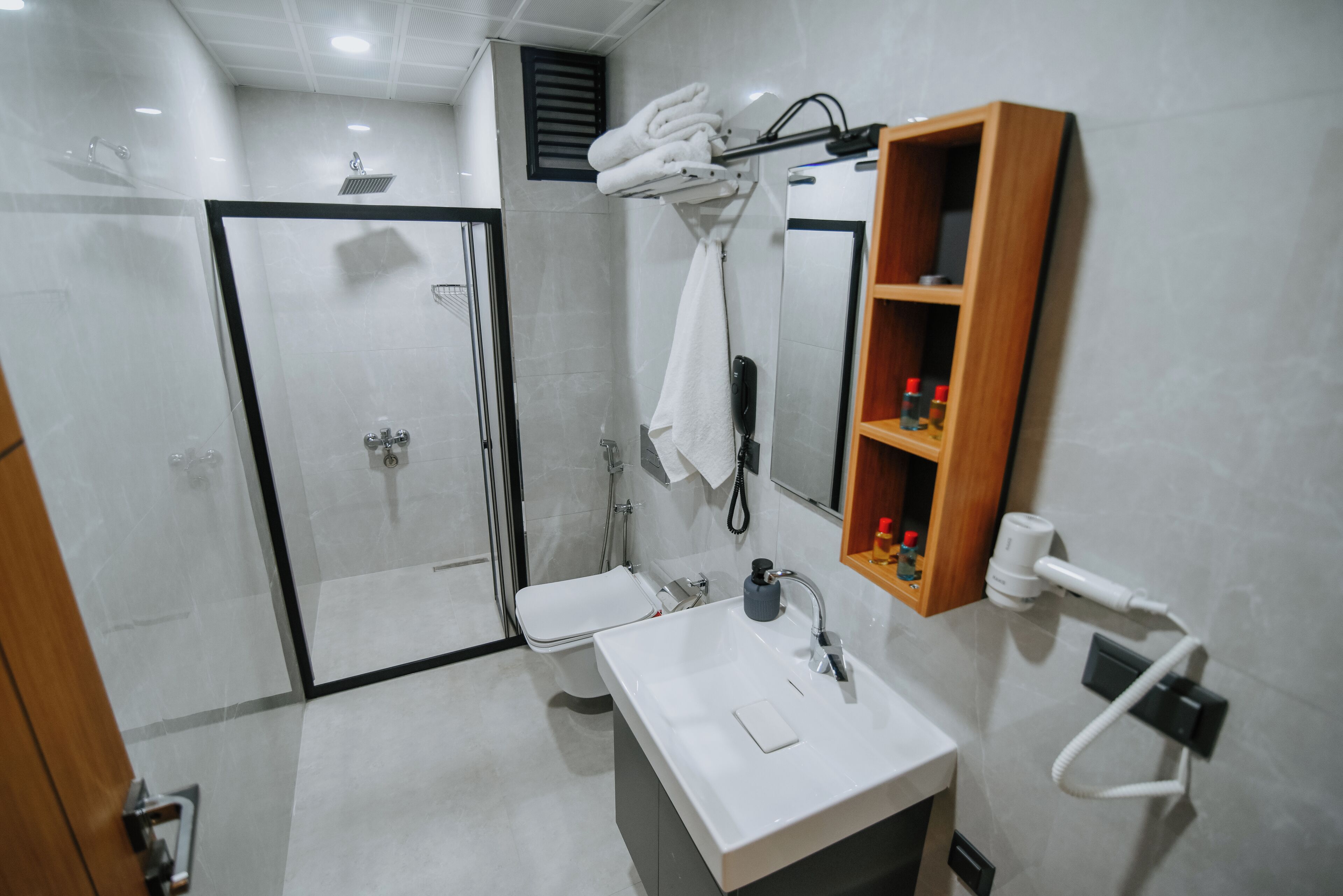 Une salle de bain moderne avec une douche à parois de verre, un lavabo blanc avec un miroir et un porte-serviettes.