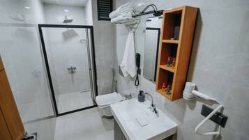 Une salle de bain moderne avec une douche à parois de verre, un lavabo blanc avec un miroir et un porte-serviettes.