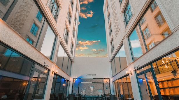 Un atrium d’hôtel doté d’un espace salon central, de plusieurs balcons et offrant une vue sur le ciel grâce à une verrière.