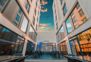A hotel atrium with a central seating area, multiple balconies, and a view of the sky through the ceiling. - Aktaş Lights Hotel (Trabzon)