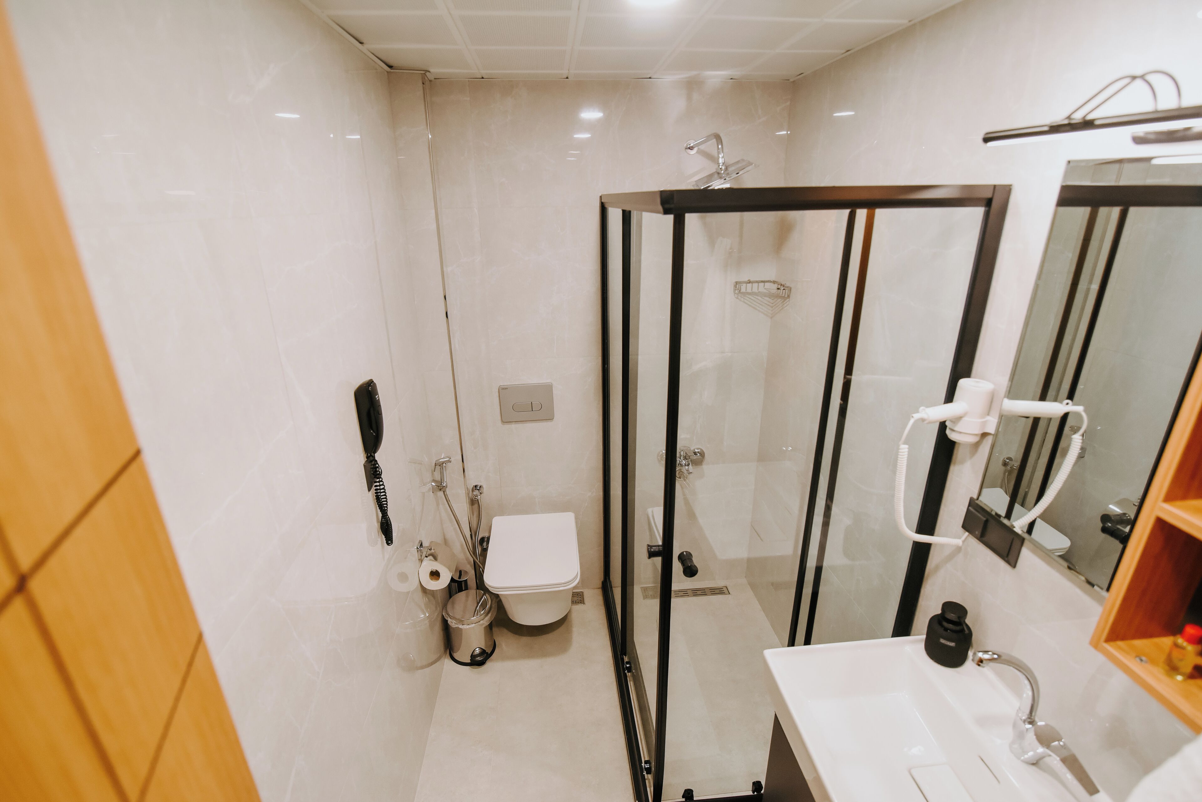 A modern bathroom with a glass-enclosed shower, a white sink, and a mirror.