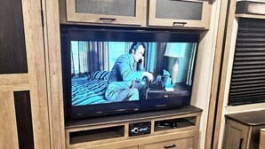 Un televisor sobre un mueble de madera con un gabinete incorporado abajo.