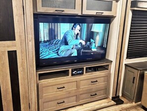Television mounted on a cabinet with a shelf and drawers below.