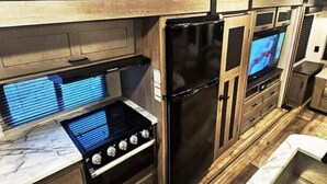 Una cocina compacta con horno empotrado, refrigerador y microondas.