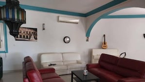 Un soggiorno con un divano in pelle rossa, un divano bianco, un tavolino da caffè nero e una chitarra su un mobiletto.