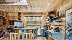 Un interior de madera acogedor con una zona de bar, una mesa de comedor y una cocina.