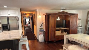 A kitchen with a refrigerator, a dining area with a table and chairs, and a hallway leading to a living room. - South Tampa! Stay Steps from Bayshore Near MacDill AFB (Tampa)
