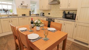 Een moderne keuken met houten kastjes, een eettafel gedekt voor vier personen en een inbouwoven.