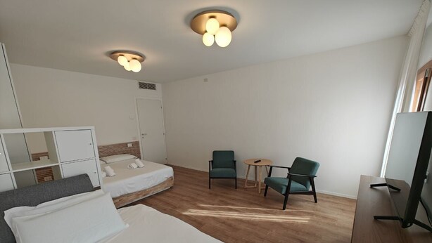 Ett hotellrum med två sängar, ett skrivbord, en TV och en sittgrupp med stolar.
