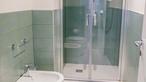 A bathroom with a glass-enclosed shower, a toilet, and a bidet.
