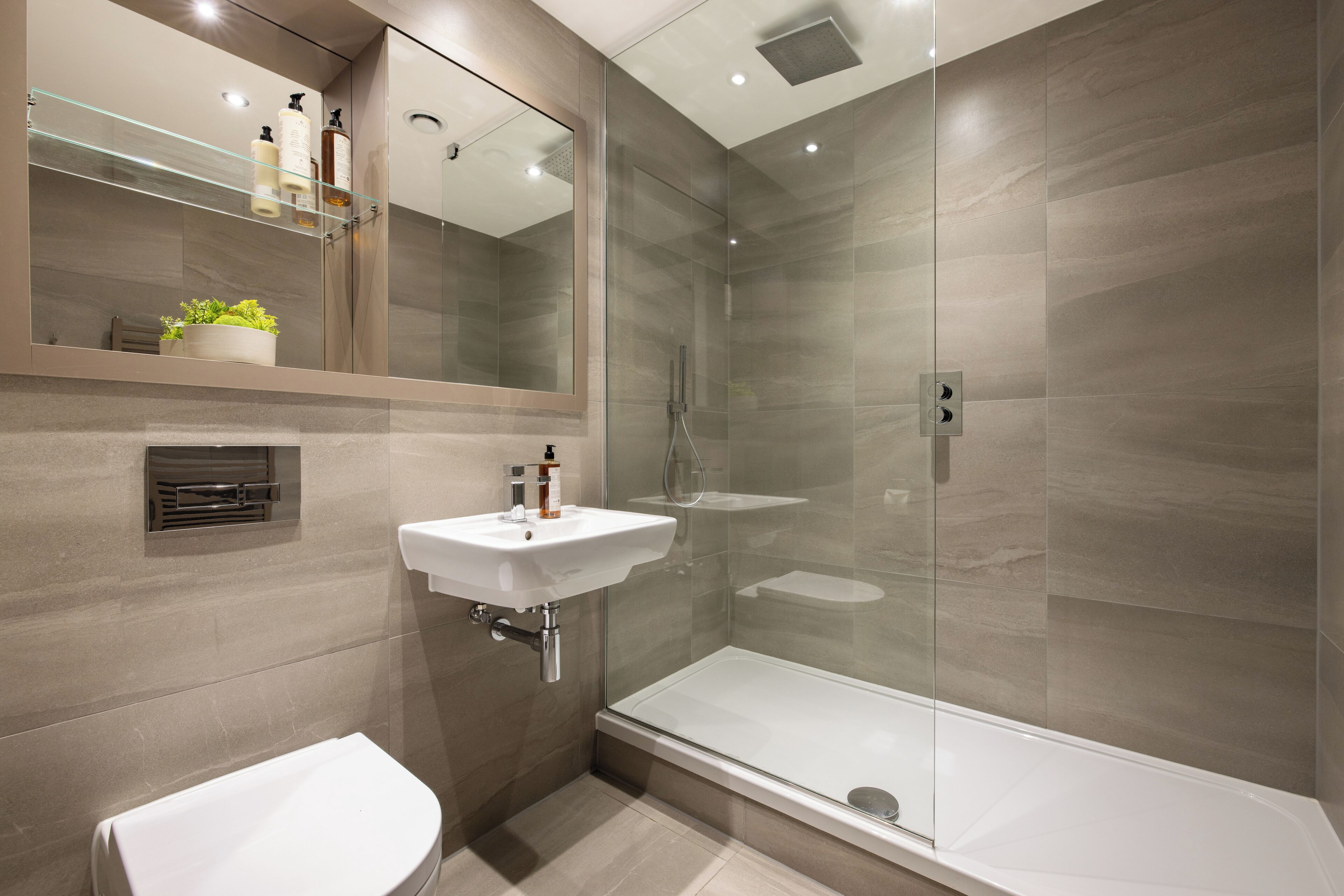 A modern bathroom with a glass-enclosed shower, a white sink, and a toilet.