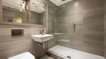 A modern bathroom with a glass-enclosed shower, a white sink, and a toilet.