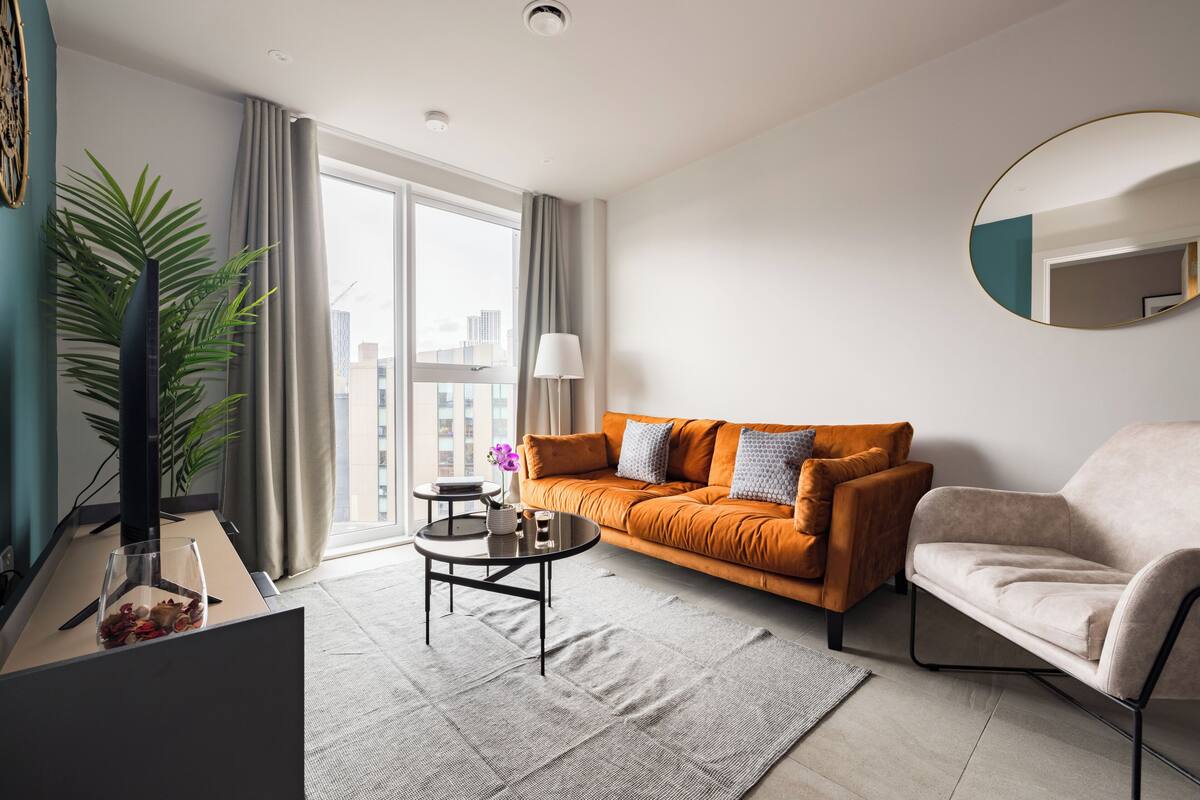 A modern living room with a sofa, armchair, coffee table, and a large window.
