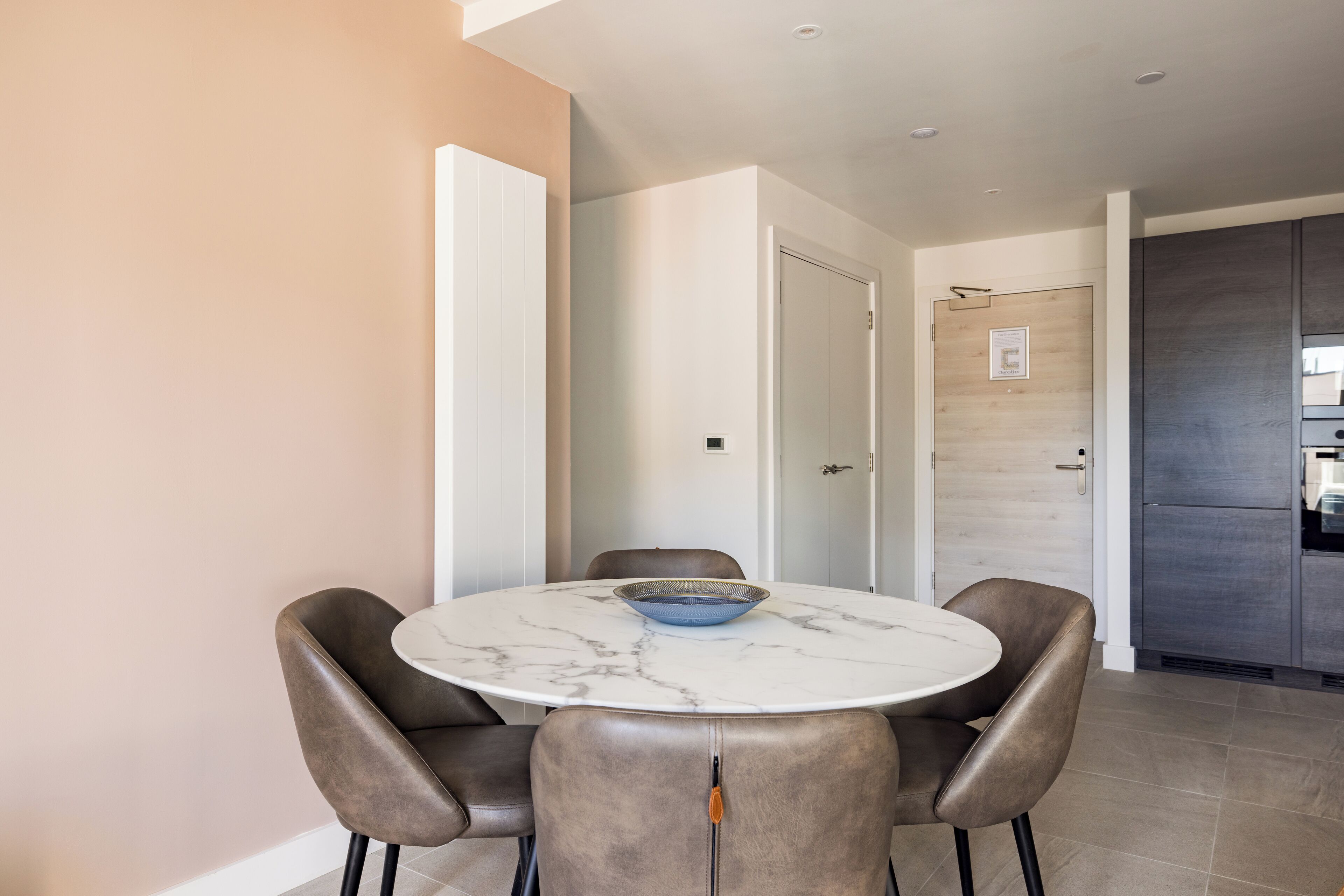 A modern dining area with a round table, two chairs, and a bowl.