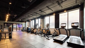 Une salle de sport équipée de tapis de course, de vélos elliptiques et de matériel de musculation.