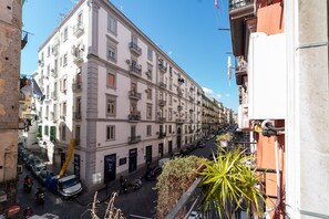 A multi-story building with balconies, a street with parked cars, and a clear blue sky. - Rosaroll 70 Apartment by Wonderful Italy (Napoli)