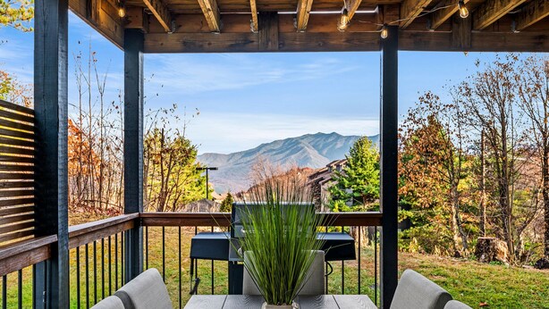 A covered outdoor seating area with a view of mountains and autumn foliage.