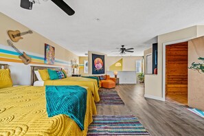 Habitación de hotel con cama, escritorio, silla, ventilador de techo y ventana.
