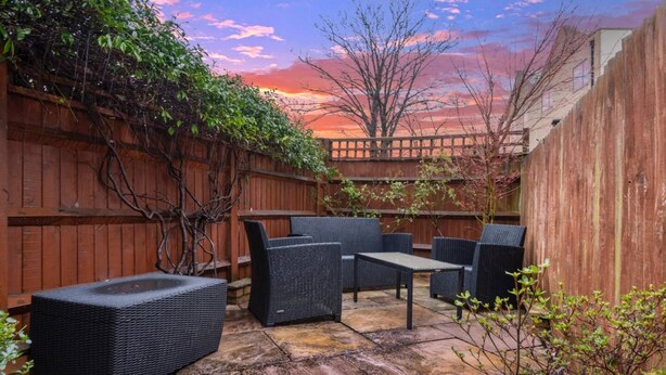 A patio with wicker furniture, a stone floor, and a wooden fence. - Ground Floor Apartment - Private Garden (London)