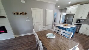 A modern kitchen with white cabinets, a stainless steel refrigerator, and a blue island. - Four Palms Unit D, 500ft to Beach, Walk 2 Casinos! (Biloxi)