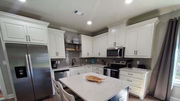 A modern kitchen with white cabinets, stainless steel appliances, and a central island. - Four Palms Unit D, 500ft to Beach, Walk 2 Casinos! (Biloxi)