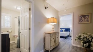 A hallway with a bed, a nightstand, a lamp, and a door leading to another room. - Pet friendly, huge fenced in yard, Fireplace, Firepit, near SGMC & VSU & Eats (Valdosta)