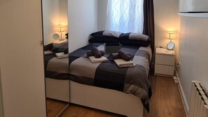 Ein modernes Schlafzimmer mit einem Bett, Nachttischen, einem Spiegel und einer Deckenleuchte.