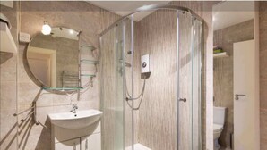 Ein modernes Badezimmer mit einer Glasdusche, einem runden Spiegel und einem weißen Waschbecken.