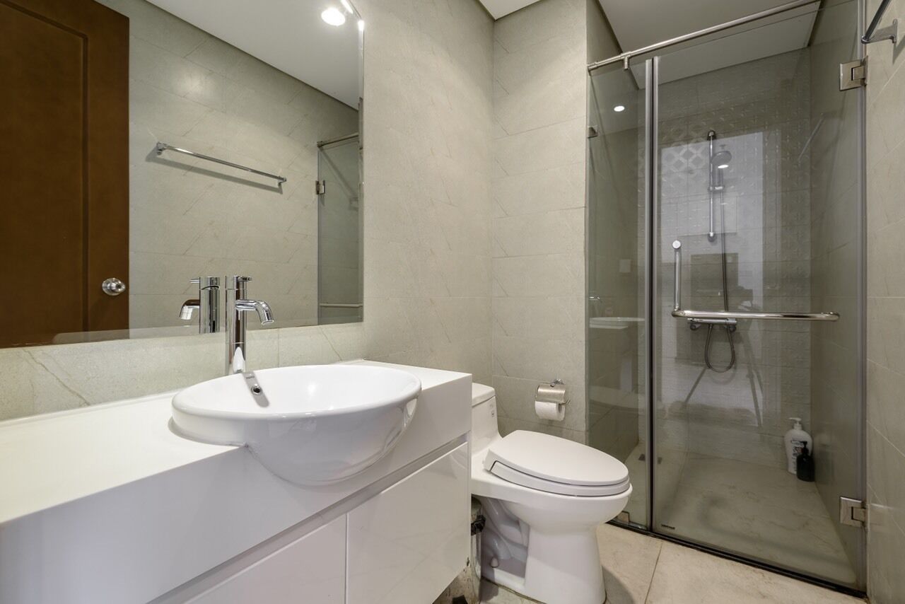 A modern bathroom with a white sink, a toilet, and a glass-enclosed shower.