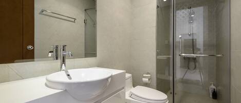 A modern bathroom with a white sink, a toilet, and a glass-enclosed shower.