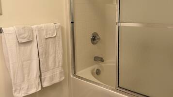 A bathroom with a glass-enclosed shower, a bathtub, and a towel rack with two towels.