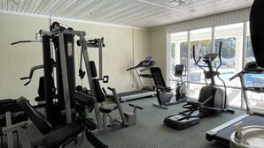 A gym with various exercise equipment, including treadmills and weight machines, and large windows providing natural light. - Beaches and Birdies II -  First Floor Golf Resort Studio (Calabash)