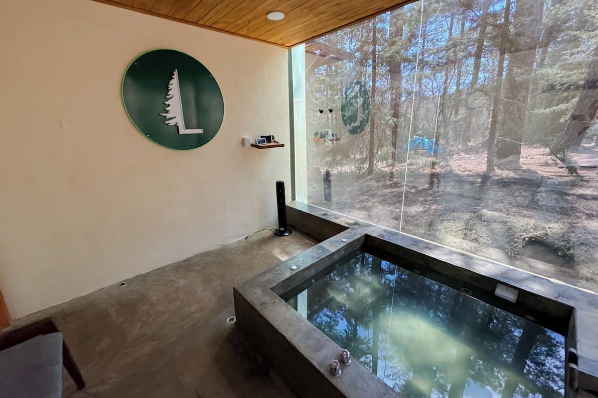 Ein Spa-Raum mit großem Fenster, Holzboden, einer runden Wanddekoration und einer Whirlpool-Badewanne.
