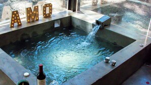 A hot tub with the letters "AMO" illuminated, a bottle of wine, and glasses on the side. - Luahara Glamping Tapalpa – Domo Natural Experience (Tapalpa)