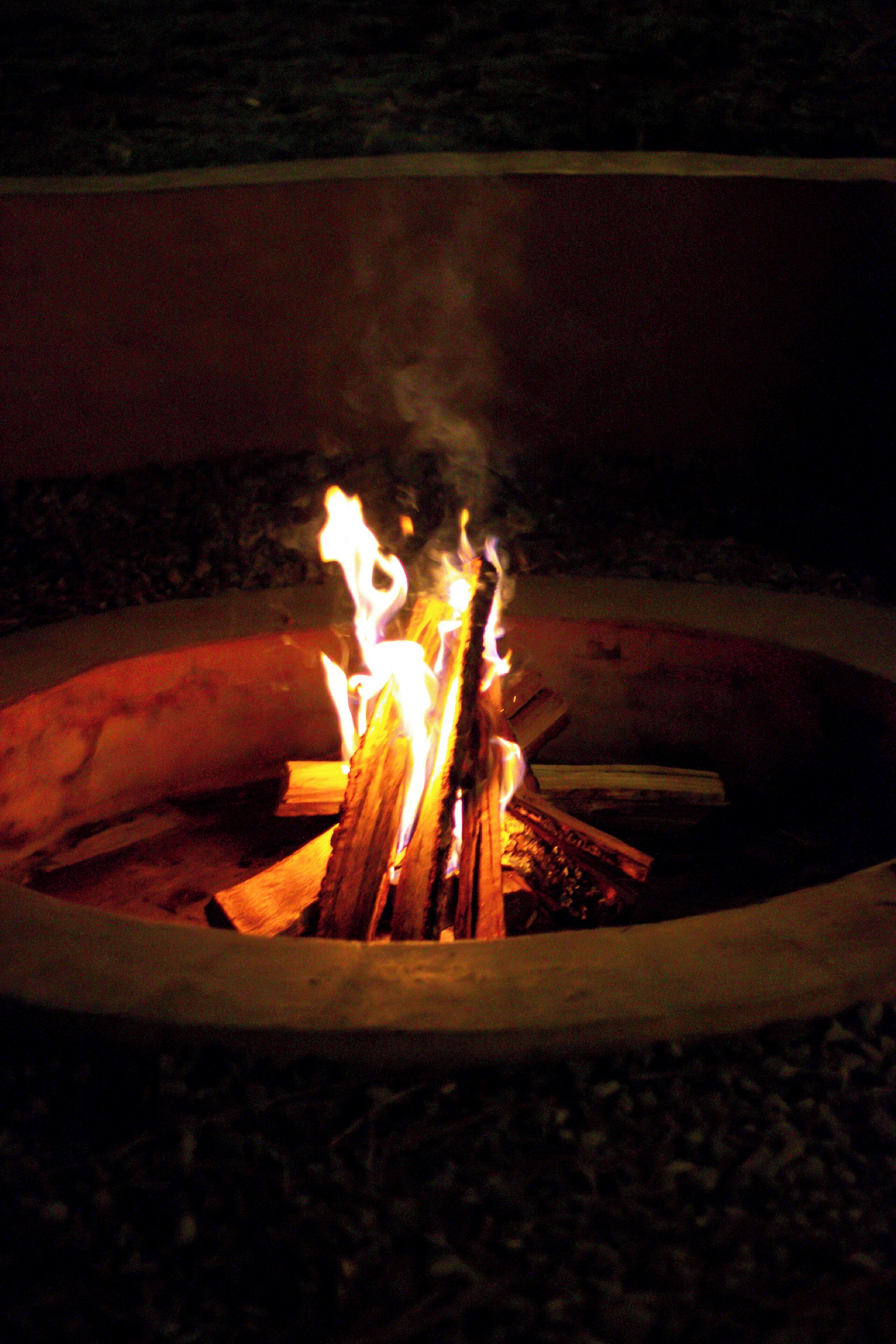 Un hogar circular con leña ardiendo y llamas.