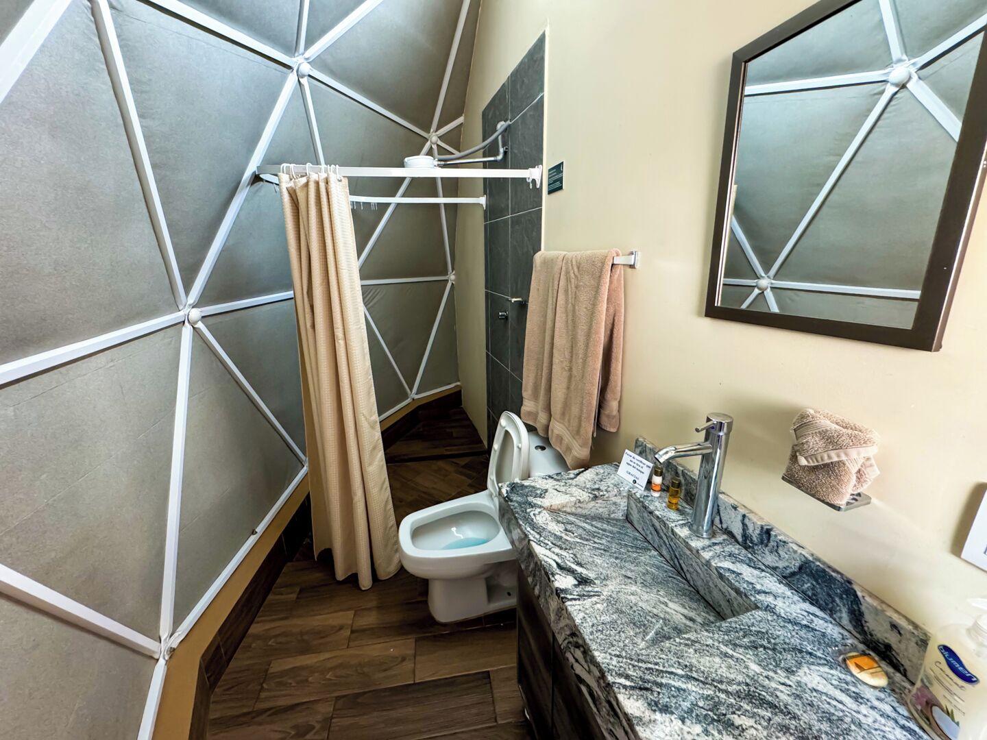 Ein Badezimmer mit modernem geometrischen Wanddesign, einer Toilette, einem Waschbecken mit Marmorplatte und einer Duschvorhang.