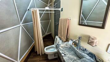 Ein Badezimmer mit modernem geometrischen Wanddesign, einer Toilette, einem Waschbecken mit Marmorplatte und einer Duschvorhang.