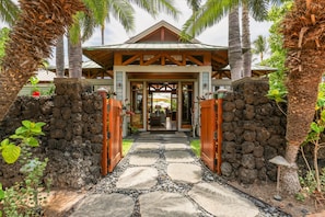 A stone pathway leading to a wooden gate with a building in the background.