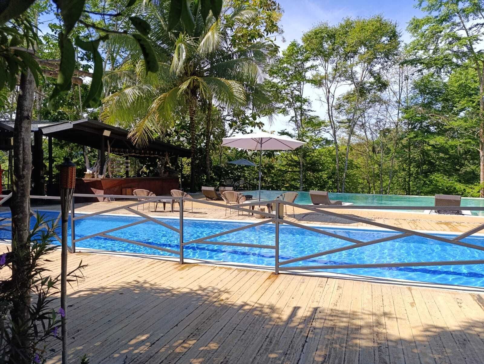 A pool area with a wooden deck, lounge chairs, and umbrellas.