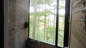 Une salle de bain avec une grande fenêtre, des murs en bois et un espace douche.