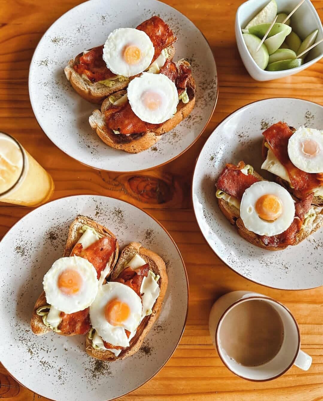 Four plates of food with toast, eggs, and bacon.