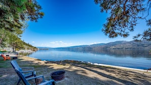 Vista d'un llac amb una panxa i una galleda, envoltat d'arbres i un cel clar.