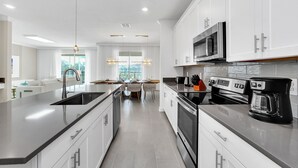A modern kitchen with white cabinets, stainless steel appliances, and a central island. - Ultimate Bespoke 6 Bedroom Champions Gate Pool Villa (Davenport)