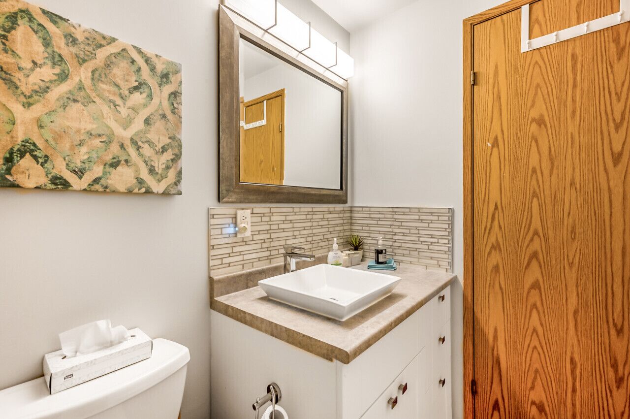 A bathroom with a white sink, a mirror, and a wooden door.
