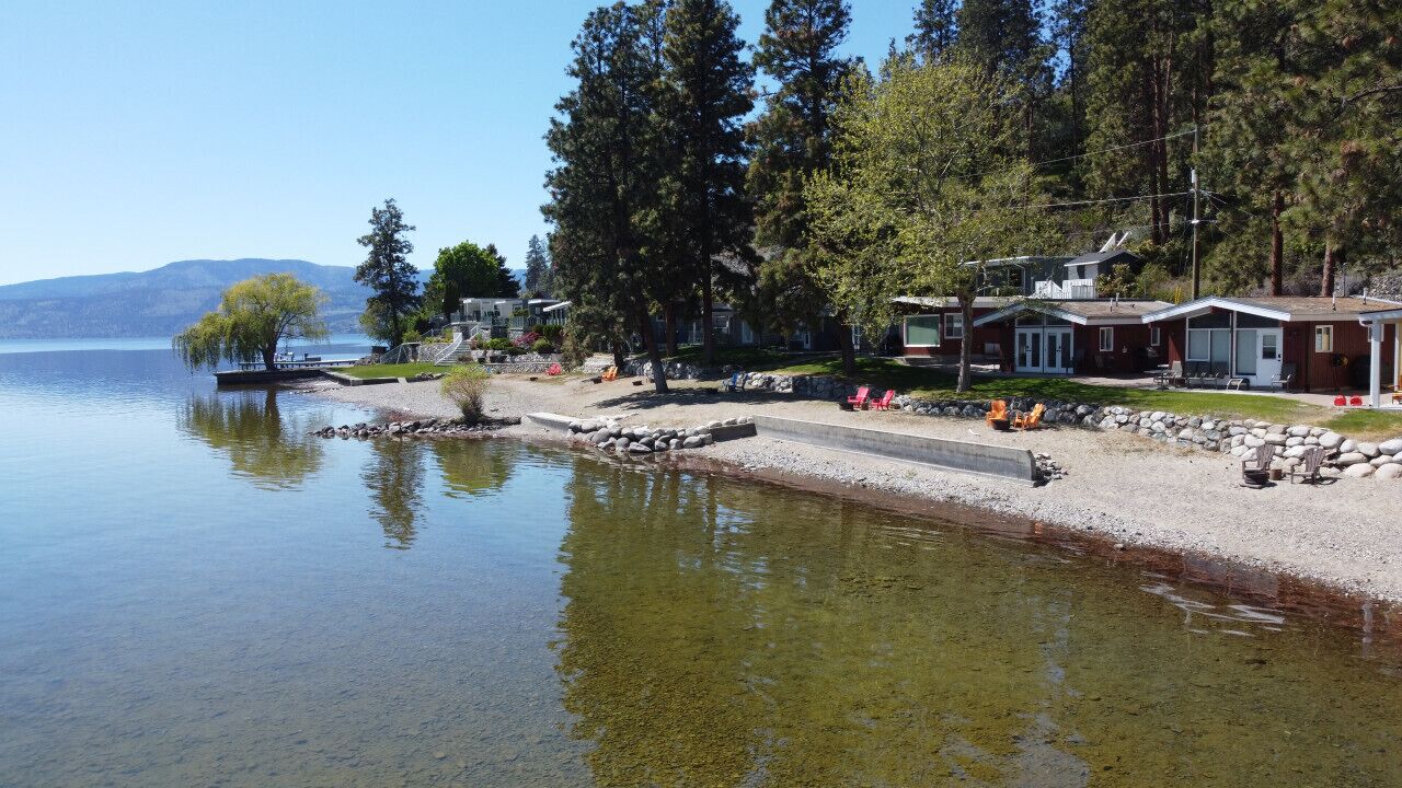 A lakeside property with cabins, a dock, and a clear view of the lake.