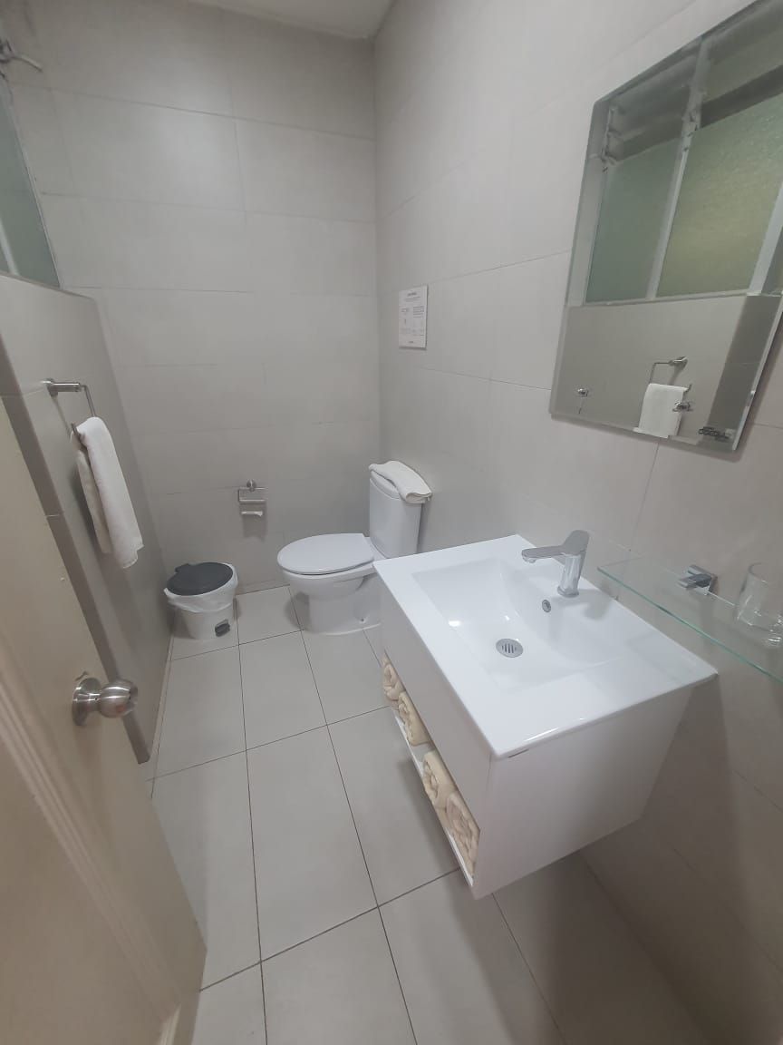 A small, clean bathroom with a white sink, toilet, and bidet.